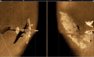A pair of images depicting a plane flying above a large island, highlighting the region analyzed with side-scan sonar.
